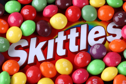 Bag of Skittles with candies strewn across the bag